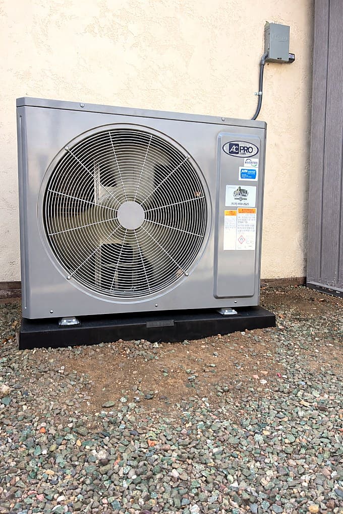 A newly installed outdoor AC condenser on a level pad beside a stucco home